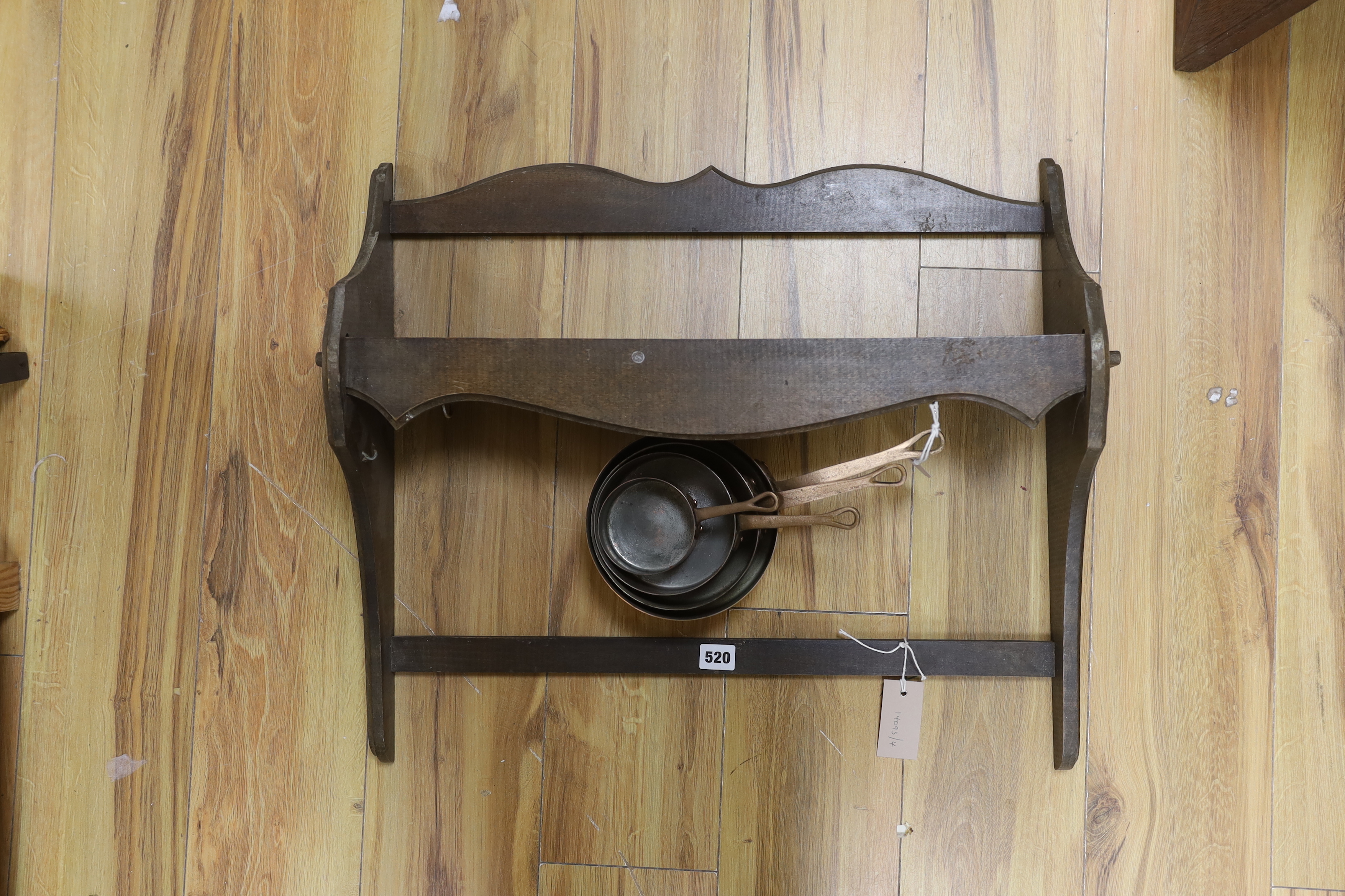 A graduated set of four copper and brass handled saucepans with a beech hanging wall rack, rack approximately 64cm wide